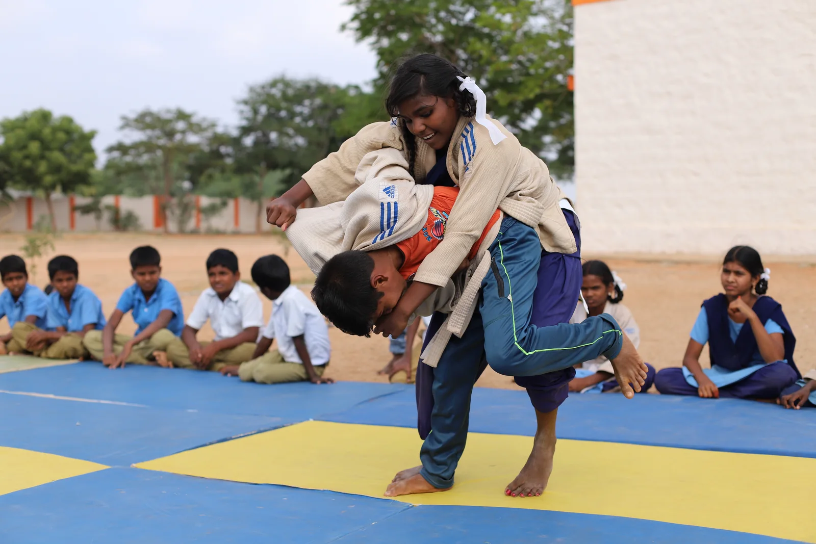 Two ASA judo athletes practising a throw while other young athletes watch